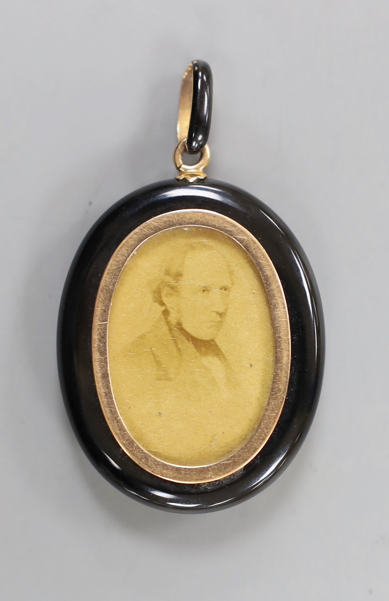 A Victorian black enamelled yellow metal oval locket, set with an old cut white sapphire, overall 62mm.